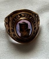 Top view showing purple stone, oval design, and 'STUDIOUS PHILLIS WHITNEY' engraving around stone.