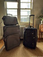 Two gray Skyway suitcases (one large, one carry-on) and one medium blue Samsonite suitcase arranged in front of a window with natural light, showing front and side views.
