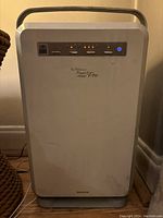 Front view of a white rectangular air purifier with control buttons and indicator lights on the front panel. Shows Nikken Air Wellness Power 5 Pro branding.