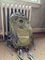 Front view of olive green Osprey Stratos 24 backpack showing wear, main compartment, front pocket, and straps.
