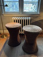 Two hourglass-shaped rope-wrapped end tables positioned near a window