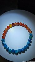 Bracelet showing alternating natural red/orange and blue agate beads arranged in a circle on a white background.