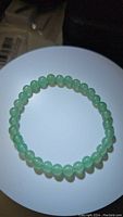 Top view of the natural green aventurine bead stretchy bracelet laid flat, showing the round beads with smooth polish and consistent light green color.