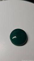 Top view of round green onyx cabochon gemstone showing glossy surface and deep green color under bright lighting