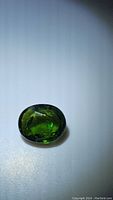 Photo of the oval cut, deep green tourmaline gemstone showing color and cut details
