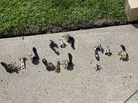 Overview of four used black lever door passage handles with latches and mounting parts laid out on concrete