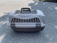 Front view of plastic pet carrier showing ventilation slats and top carrying handle.