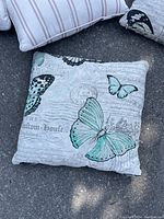 Close-up of square throw pillow showing butterflies and script design