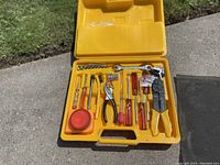 Yellow open case showing tools and road safety items laid out in molded compartments