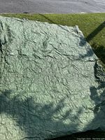 Green tarp laid out on grass showing surface texture and condition