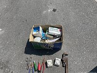Overview shot of the tools and box of light bulbs on asphalt, showing all items laid out.