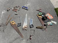 Full overview showing layout of hand saws, clamps, files, clamps, brushes, and small tools arranged on ground.