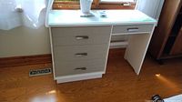Front view of white painted wood desk with four drawers and glass top, showing modern handles and clean surface.