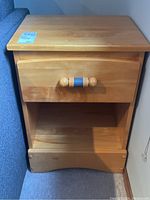 Front view of wood end table closed drawer showing rounded wooden handle with blue accent.