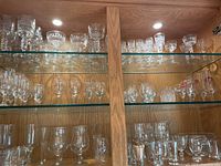 Full view of three shelves with assorted glassware including stemmed glasses, tumblers, and specialty glasses.