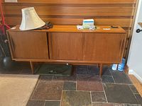 Front view of three-door wood cabinet with tapered legs