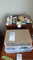 Top view of brown vintage plastic sewing box showing many spools of thread inside compartments along with scissors and other notions.