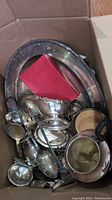 Box containing tarnished silver plated trays, bowls, various serving spoons and utensils, some utensils missing handles