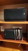 Two black Cerwin-Vega speakers stacked on shelves, one wrapped with speaker wire.
