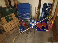 Full overview of all camping and sports items grouped together including chairs, hockey stick, rackets, gloves, backpacks and other gear.
