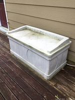 Side angle view of resin deck box showing length, height, and surface wear.