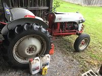 Front left view showing rear tire, white and yellow oil containers, tractor body