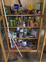 Full view of cabinet with shelves displaying paints, brushes, scrapers, roller pole.