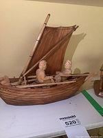 Front and side view showing the detailed carving of the fishermen and boat hull with sail.