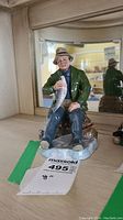 Front view of Royal Doulton figurine showing seated fisherman holding fish