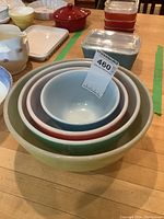 Photo showing set of nesting Pyrex mixing bowls in primary colors inside a larger bowl on a wooden surface.
