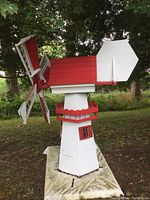 Front view of wooden windmill showing tower, balcony rail and rotating blade assembly