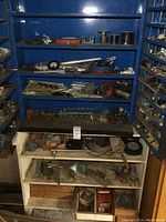 Front view of blue metal cabinet with shelves filled with wires, tools, and hardware items.