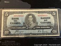 Front view of the 1937 Canadian five dollar banknote showing the portrait of King George VI, serial numbers, signatures, and text in both English and French.