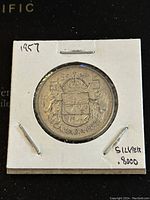 Reverse side of the 1957 Canadian 50 cent silver coin showing detailed Canadian Coat of Arms and date 1957.