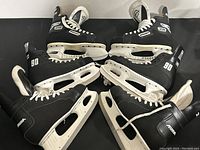 Three pairs of black hockey skates arranged with blades facing inward