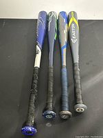 Four assorted aluminum baseball bats placed side by side showing grip and length variation.