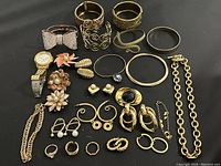 Overview of assorted gold tone jewelry including rings, bracelets, earrings, pins and untested watch