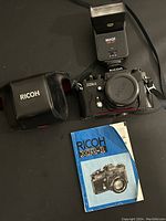 Ricoh XR-1s camera body with lens attached, Image CB-21 flash sitting behind it, Ricoh branded camera case on left, and original blue manual booklet below camera.