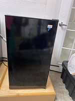 Front view of the black mini fridge, shows full single door and general condition.