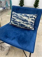 Blue oversized chair with one rectangular blue and white patterned pillow on seat.