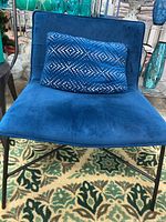 Blue oversized chair with plush velvet upholstery, metal leg frame, and a blue cushion with silver geometric stud detailing.