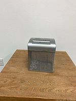 Front view of the Fellowes ShredMate paper shredder showing metal mesh waste bin and silver top panel with controls.