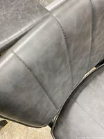 Close-up of the gray leather style upholstery with vertical stitching on chair seat and backrest.