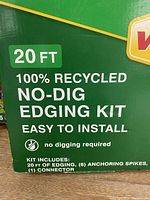 Close-up of the green box showing 20 ft, 100% recycled no-dig edging kit text and contents: 20 ft edging, 6 anchoring spikes, 1 connector
