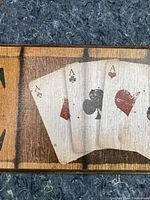 Close-up of center block showing four aces playing cards on wooden sign