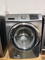 Full frontal view of silver front load washer showing door and control panel