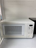 Front view of the white Emerson microwave with closed door showing the control panel and glass window.