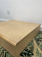 Close-up corner view showing wood texture and rounded edges of the display platform.