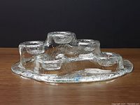 Side profile view of the clear textured glass candleholder showing the varying heights of 6 votive candle placements in a volcano inspired shape.