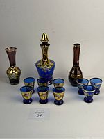 Full lot including the cobalt blue decanter, two vases, and two sets of cobalt blue shot glasses with gold floral accents.